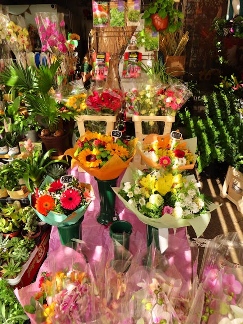 A vibrant display of fresh flower bouquets arranged on a table inside a flower shop, showcasing an assortment of floral arrangements with bright, colorful blooms including yellow, orange, pink, and wh